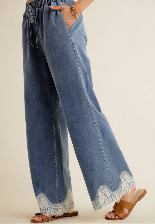 Blue denim pants with lace trim on a beige background
