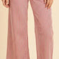 A person wearing wide-leg pants with vertical red and white stripes, paired with tan slide sandals, against a plain beige studio background.