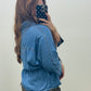 A woman taking a mirror selfie wearing a light blue denim top and leopard print pants, showing off the side view of the outfit.