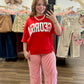 A woman takes a mirror selfie in a clothing boutique wearing a red sweatshirt with white 'GEORGIA' lettering and red-and-white striped wide-leg pants.