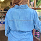 A person viewed from behind wearing a light blue denim top paired with leopard jeans, standing in a store interior.