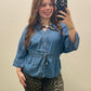 A woman taking a mirror selfie wearing a blue denim button-up shirt with a drawstring waist and a patterned neck scarf, paired with leopard print pants.
