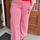 A person wearing red and white vertically striped wide-leg pants, paired with a bright red top and brown sandals.