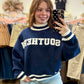 Mirror selfie taken in a clothing boutique, wearing a navy blue varsity-style sweatshirt with 'SOUTHERN' printed in white across the chest and light blue jeans.
