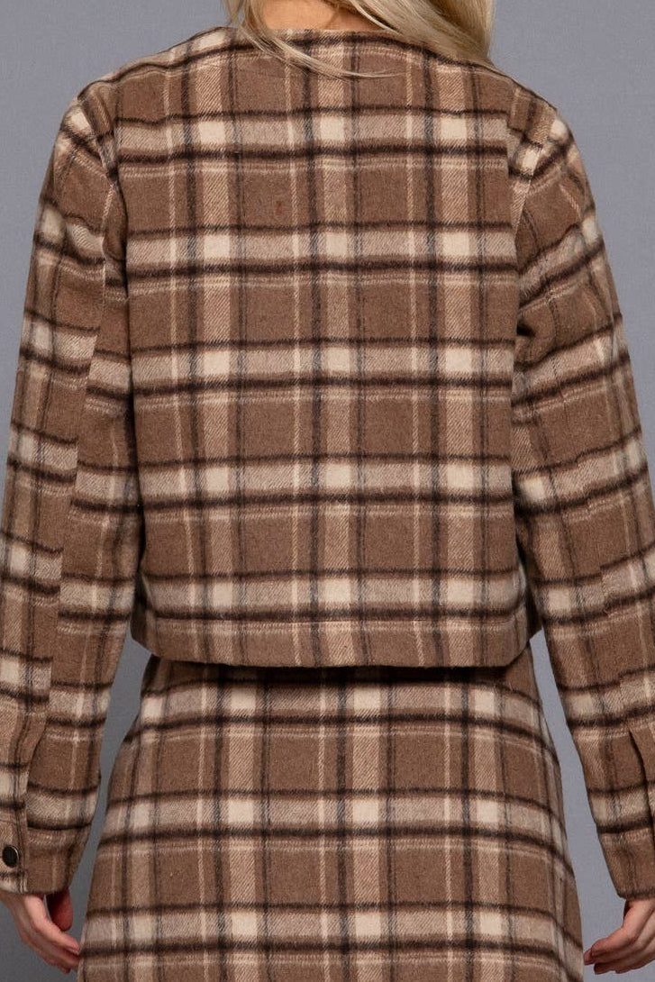A woman shown from the back wearing a brown and beige plaid cropped jacket and matching mini skirt against a solid gray studio background.