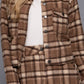 A model wearing a brown and beige plaid button-up jacket and matching mini skirt over a white top, photographed against a solid gray studio background.